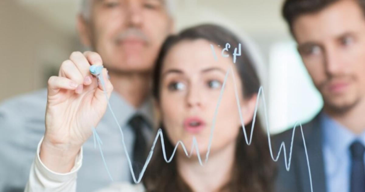 Foto de tres personas mirando unas gráficas sobre un vidrio