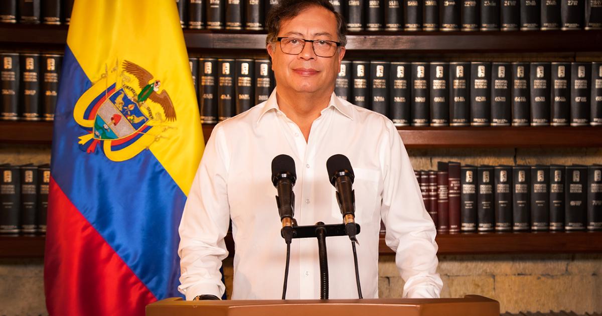 Foto de un hombre parado detrás de un atril y con camiseta blanca