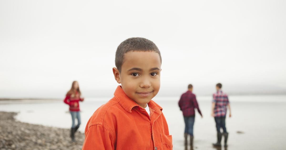Foto de un niño  con camiseta naranja mirando a la cámara 