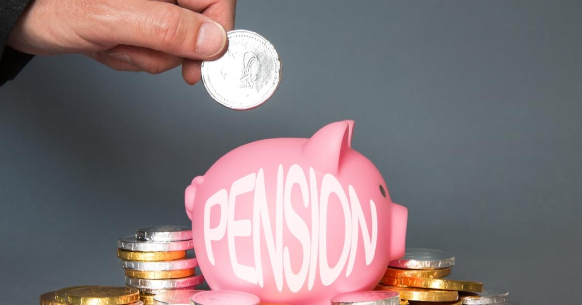 Foto de una persona depositando una moneda en un marrano rosado