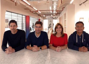 Foto de cuatro personas reunidas en una mesa mirando a la cámara