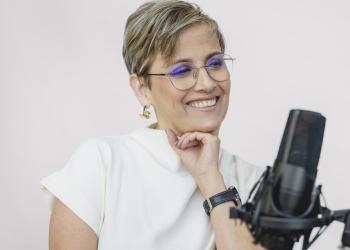 Foto de Patricia Velásquez, una mujer sonriente con un micrófono de frente