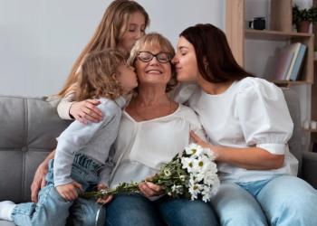 Foto de dos hijas besajndo a su mamá en la mejilla