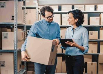 Foto de dos personas hablando con cajas de fondo