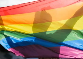 Foto de la silueta de un hombre detrás de una bandera inclusiva