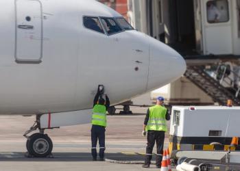 Foto de la trompa de un avión con dos personas debajo