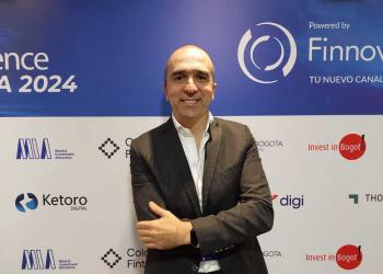 Foto de un ejecutivo mirando a la cámara con un fondo d eun evento promocional