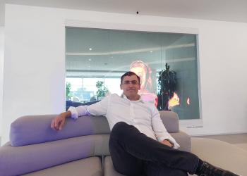 Foto de un hombre sentado sobre un sofa mirando la cámara con la pierna cruzada