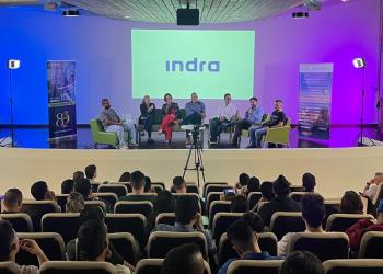 Foto de un panel con varias personas sentadas conversando frente a un auditorio