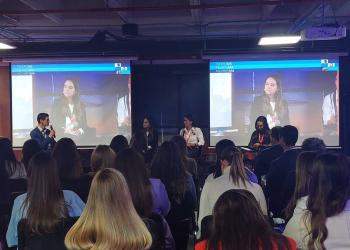Foto de un salón lleno de personas con mujeres panelistas