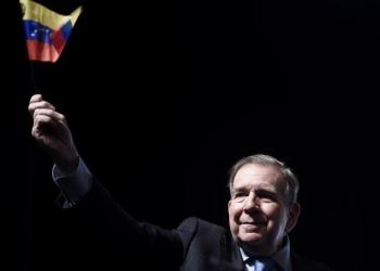 Foto de un señor con la bandera de venezuela en la mano derecha