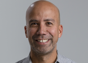 Foto de un hombre sonriente con un fondo gris