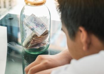 Foto de un señor mirando un frasco con dinero colombiano