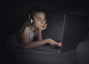 Foto de una chica mirando la computadora en la noche