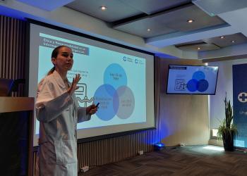 Foto de una doctora hablando frente a una pantalla 