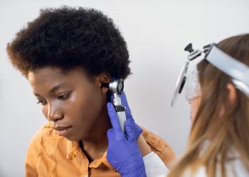Foto de una especialista revisando el oido de una mujer