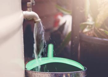 Foto de una llave de agua distribuyendo agua a un balde