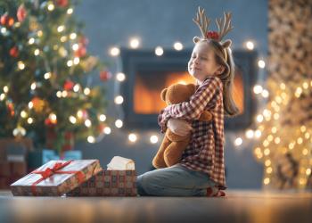 Foto de una niña con un regalo de navidad en sus brazos