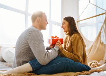 Foto de una pareja mirandose a los ojos con un regalo en sus mano