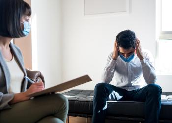 Foto de una persona agarrandose la cabeza en un consultorio