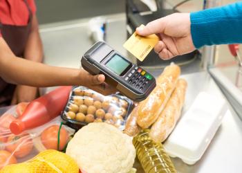Foto de una persona comprando con una tarjeta mediante un datafono