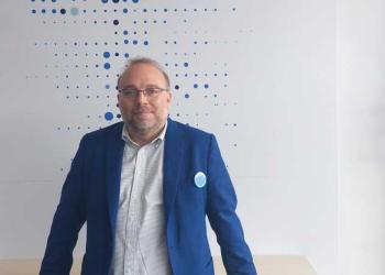 Foto de una persona con brazel y camisa azul mirando a la cámara
