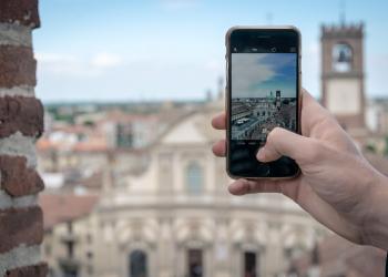 Foto de una persona tomando una fotografia con el celular y el fondo de una ciudad europea