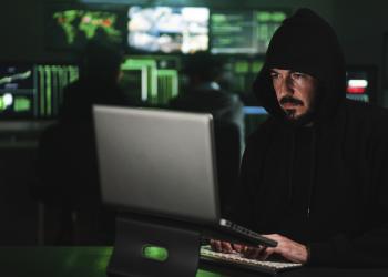 Foto de una persona trabajando con un hoodie frente a un computador