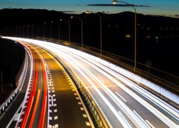Foto de una vía con efecto de cámara, los carros se ven como luces de varios colores