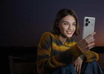 Fotografia de una mujer revisando un celular gris con un atarceder de fondo