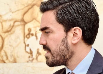 Foto de perfil de Gabriel Santos, un hombre barbudo con corbata posando de medio lado hacía la cámara