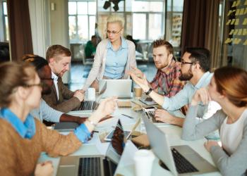 Hombres y mujeres en una mesa compartiendo ideas
