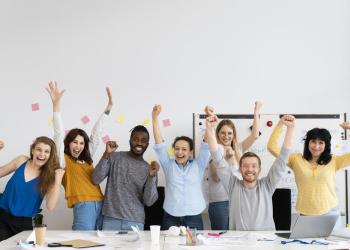 Foto de personas alzando las manos y sonriendo en sus oficinas