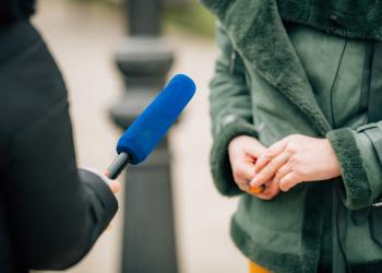 Foto de una persona con un micrófono azul entrevistando