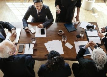 Una foto cenital de varias personas ejecutivas sentadas en una mesa