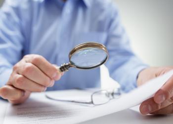 foto de una persona leyendo un documento con lupa