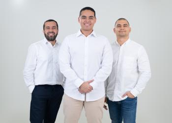 Fotografía de tres hombres con camiseta blanca mirando a la cámara