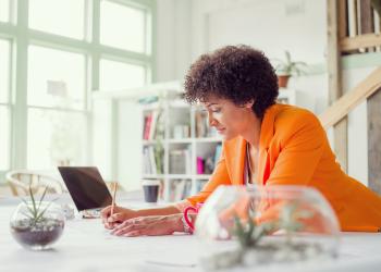 Mujer con blazer naranja mirando el computador