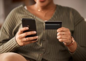 Persona sosteniendo una tarjeta en una mano y un celular en la otra