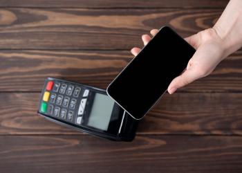 Representación de un datáfono con un celular encima, simulando un pago en línea