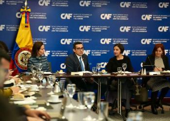 Reunión de cuatro personas sentadas en una mesa conversando
