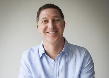 Foto de un hombre blanco con camisa azul mirando a la cámara