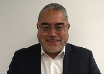 Foto de un señor con gafas blancas, mirando a la cámara con pelo hacía a trás