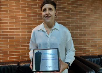 Foto de una mujer con el reconocimiento en la mano
