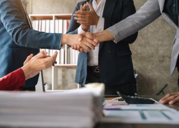 Foto de dos personas dándose la mano sobre una mesa