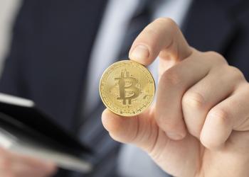 Foto de una personas sosteniendo una moneda con el logo de las cripto