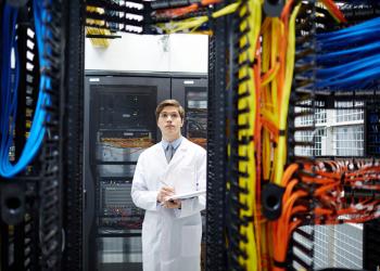 foto de un señor con bata frente a un computador grande