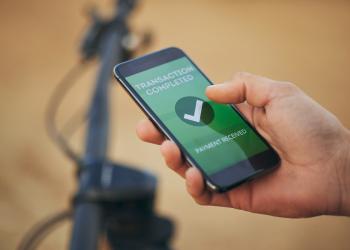 Foto de una mano sosteniendo un celular con una pantalla verde que dice transacción exitosa