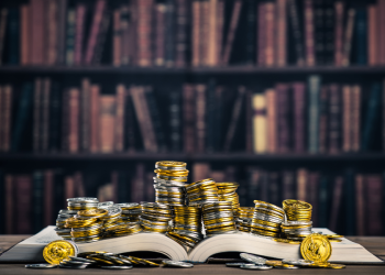 Libro abierto con monedas encima haciendo alusión a los libros de finanzas e inversiones