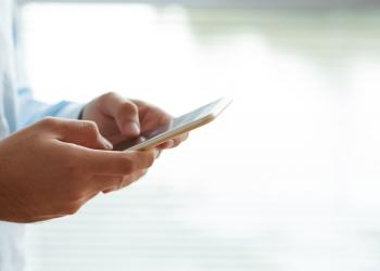Una persona mirando su celular mientras lo sostiene con las manos